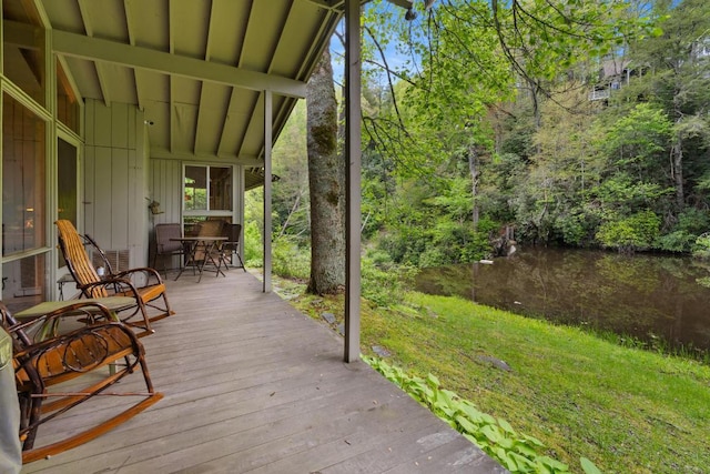 wooden deck with outdoor dining area and a lawn