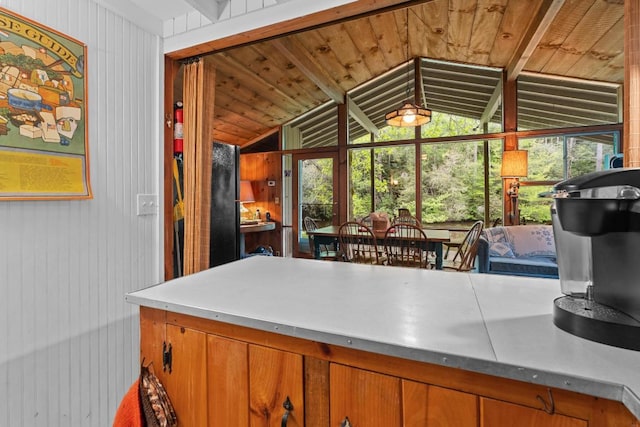 kitchen featuring lofted ceiling, brown cabinets, and wooden walls