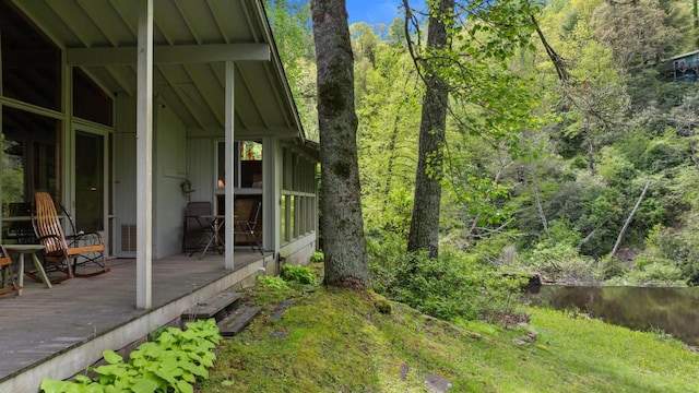 view of yard featuring a wooden deck and a forest view