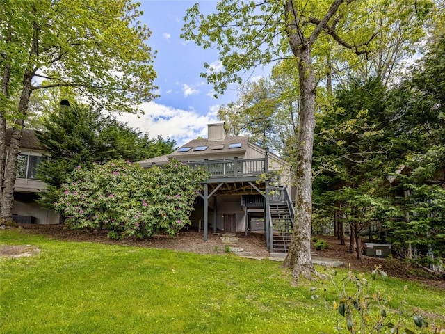 back of property featuring stairway, a wooden deck, a lawn, and a chimney
