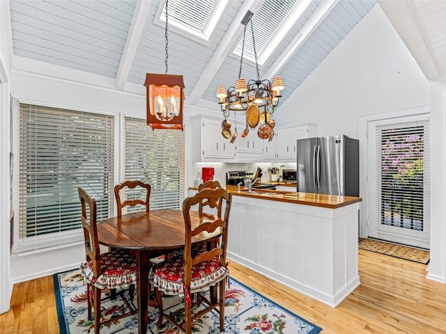 dining space with a chandelier, a skylight, beam ceiling, light wood-style flooring, and high vaulted ceiling