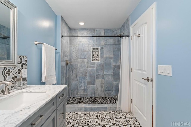 bathroom with a tile shower, tile patterned flooring, and vanity