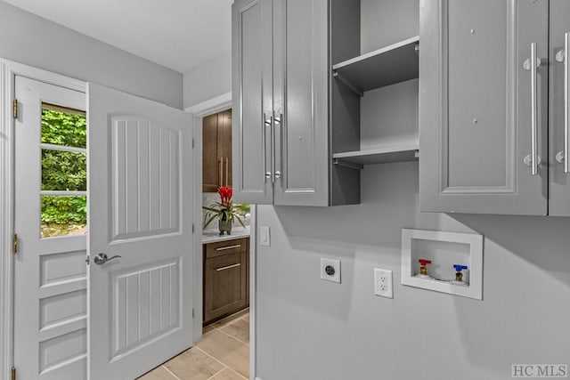 laundry area with electric dryer hookup, hookup for a washing machine, cabinet space, and light wood-type flooring