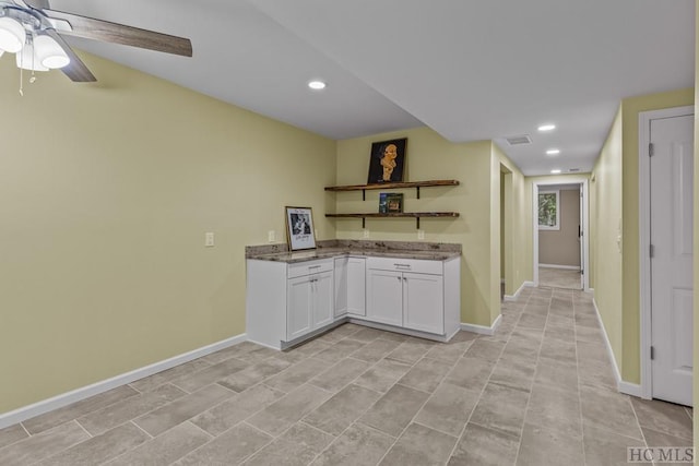 kitchen with white cabinetry, ceiling fan, and stone countertops