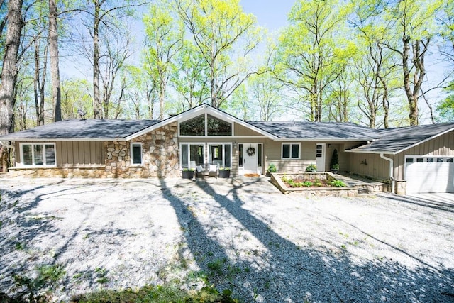 view of front of home with an attached garage, driveway, and stone siding