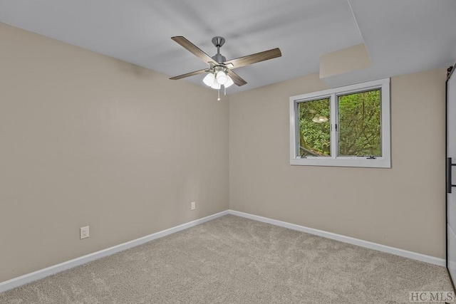 carpeted spare room featuring a ceiling fan and baseboards