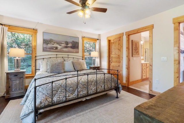 bedroom with baseboards, ensuite bath, wood finished floors, and ceiling fan
