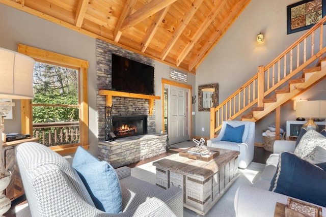 living room with stairs, wood ceiling, an outdoor stone fireplace, and beamed ceiling