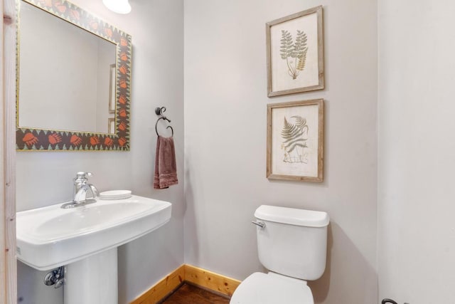 half bath with a sink, baseboards, and toilet
