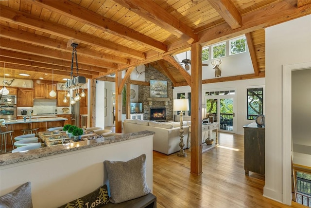 kitchen with stainless steel oven, beamed ceiling, wood ceiling, pendant lighting, and light stone counters