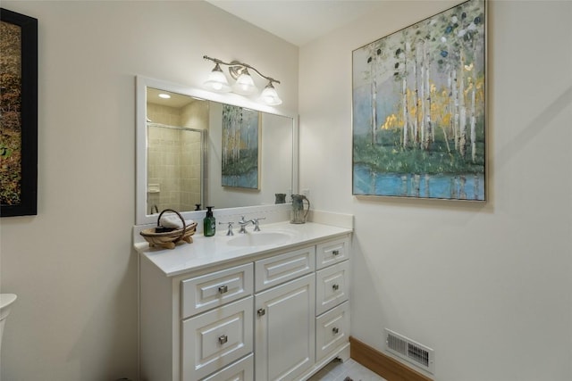 bathroom featuring a shower with shower door and vanity