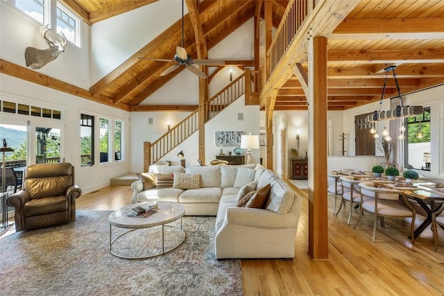 living room featuring a wealth of natural light, beam ceiling, a towering ceiling, and light wood-type flooring