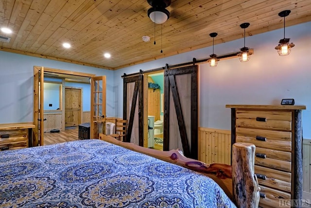 bedroom with ensuite bathroom, wood walls, hardwood / wood-style flooring, a barn door, and wooden ceiling