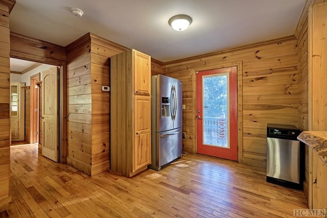 kitchen with wooden walls, stainless steel fridge, light hardwood / wood-style flooring, and light brown cabinets