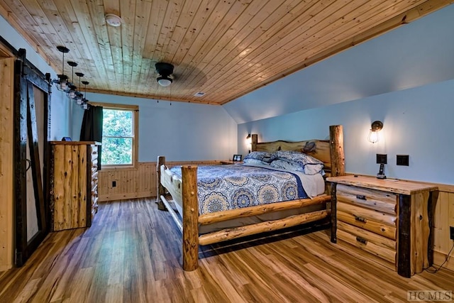 bedroom featuring vaulted ceiling, wooden walls, wood-type flooring, a barn door, and wooden ceiling