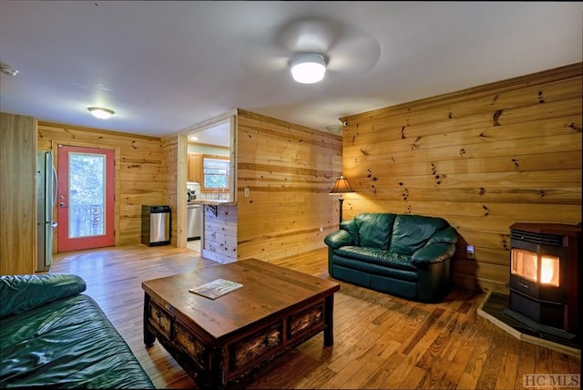 living room with a wood stove, hardwood / wood-style floors, and wooden walls