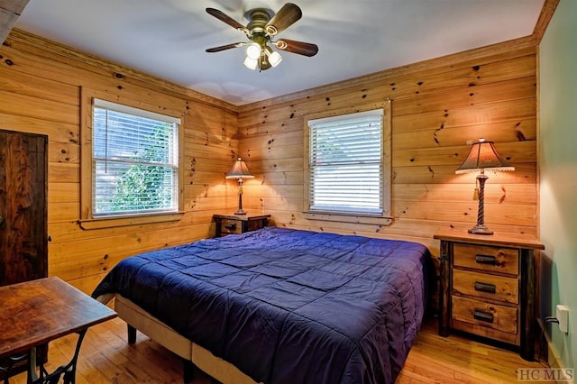 bedroom with wooden walls, light hardwood / wood-style floors, and ceiling fan