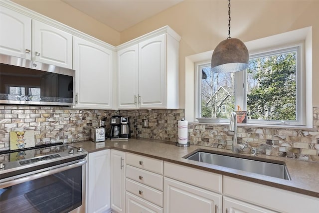 kitchen featuring stainless steel appliances, a sink, white cabinets, and decorative backsplash