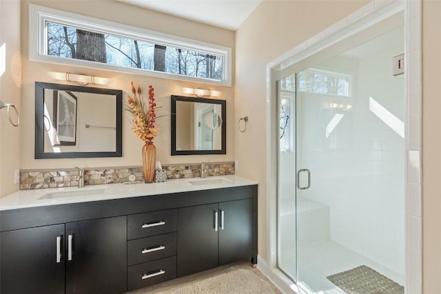 full bath featuring double vanity, a stall shower, and a sink