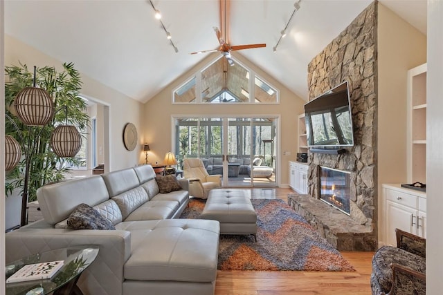 living area featuring a fireplace, high vaulted ceiling, and wood finished floors