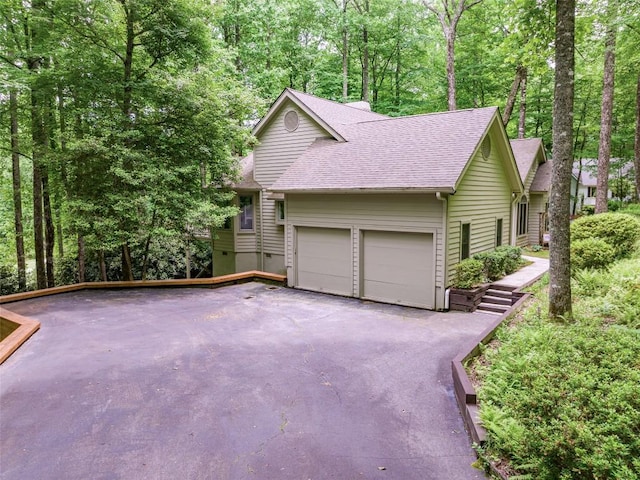 view of front of home with driveway, a shingled roof, and an attached garage