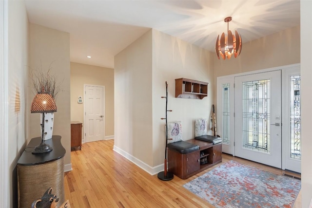 foyer with light wood-style floors, a chandelier, visible vents, and baseboards