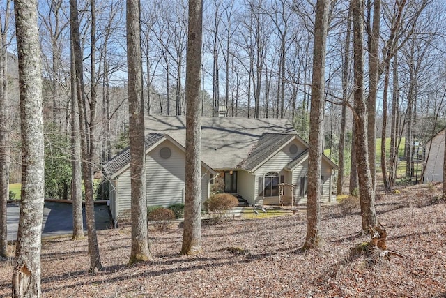 view of front of property featuring roof with shingles and driveway