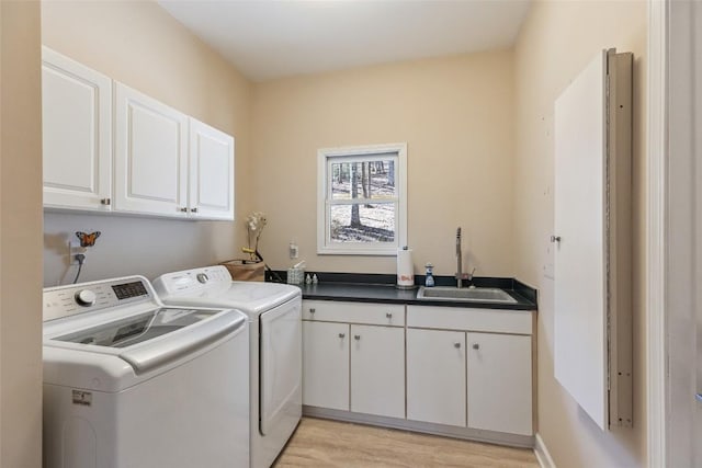 laundry room featuring light wood-type flooring, cabinet space, a sink, and separate washer and dryer