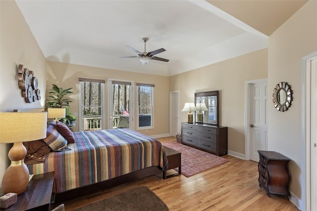 bedroom featuring a tray ceiling, light wood finished floors, lofted ceiling, ceiling fan, and baseboards