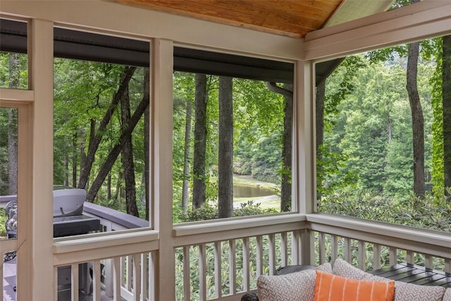 unfurnished sunroom featuring wood ceiling, a water view, and vaulted ceiling