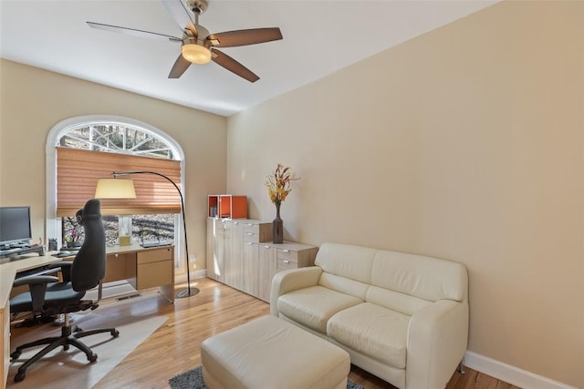 office featuring baseboards, a ceiling fan, and light wood-style floors