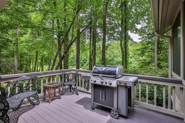 deck with grilling area and a view of trees