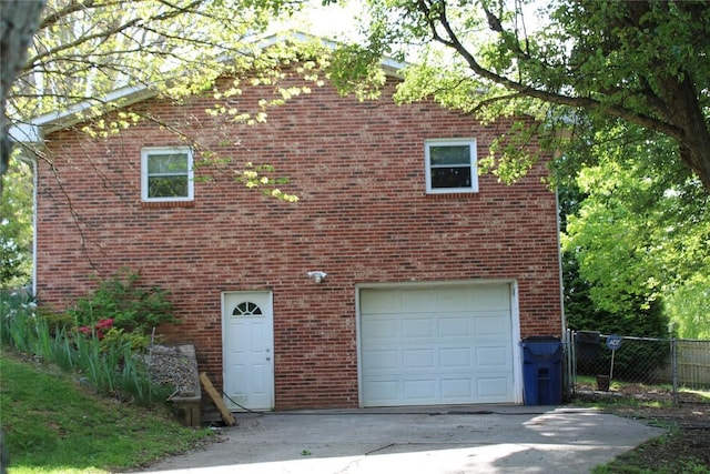 view of front facade with an attached garage, fence, driveway, and brick siding