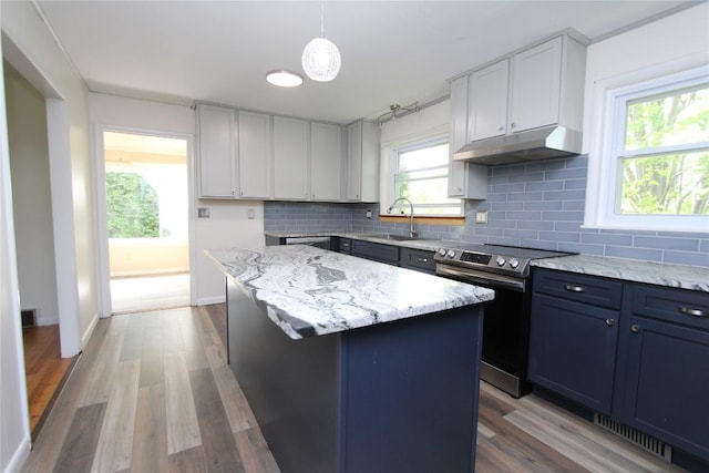 kitchen featuring stainless steel range with electric stovetop, a center island, under cabinet range hood, a sink, and backsplash