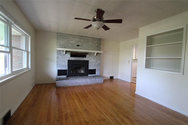 unfurnished living room with plenty of natural light, ceiling fan, wood finished floors, and visible vents