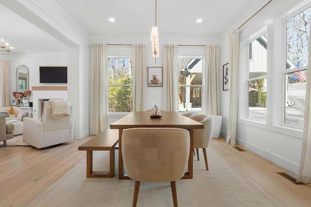 dining area featuring light wood finished floors, visible vents, a chandelier, and crown molding