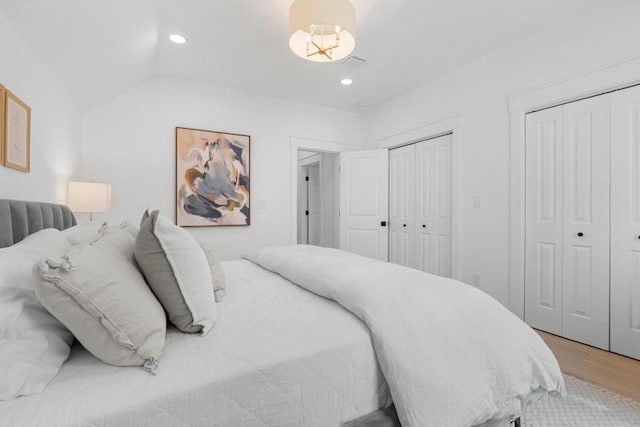 bedroom featuring visible vents, multiple closets, vaulted ceiling, recessed lighting, and light wood-style flooring