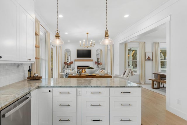 kitchen with a peninsula, white cabinets, stainless steel dishwasher, crown molding, and open floor plan