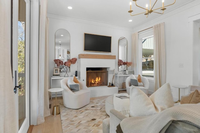 living area with crown molding, a lit fireplace, recessed lighting, an inviting chandelier, and wood finished floors