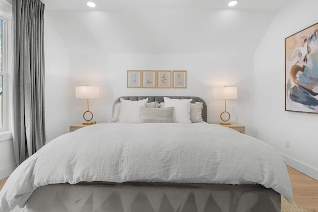 bedroom with lofted ceiling, recessed lighting, light wood-style floors, and baseboards