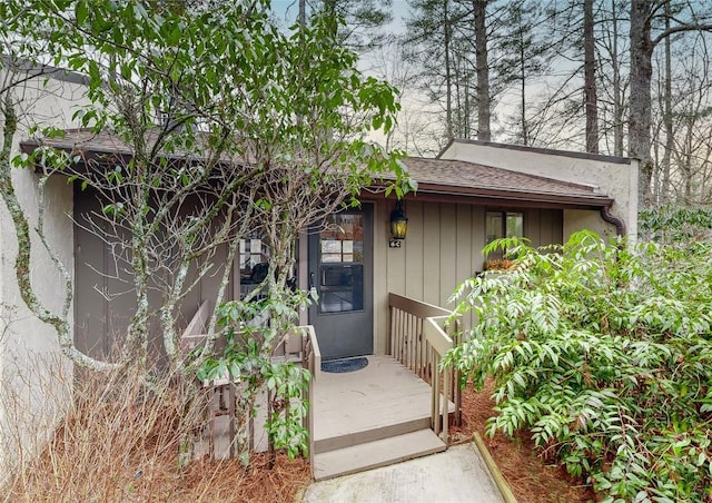 entrance to property featuring roof with shingles