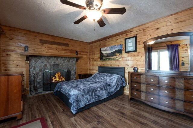 3050 N Hwy 107, Cashiers, NC 28736 - bedroom with dark wood-style flooring, a textured ceiling, a stone fireplace, and wooden walls