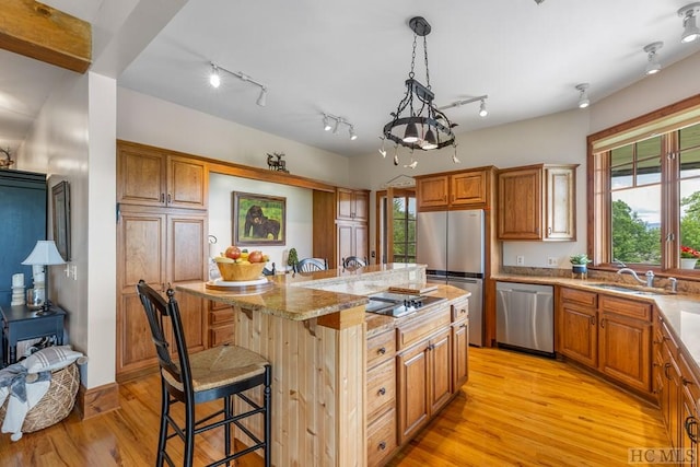 kitchen with sink, hanging light fixtures, stainless steel appliances, a center island, and a kitchen bar