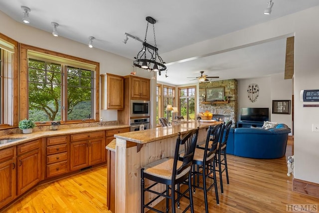 kitchen with built in microwave, stainless steel oven, hanging light fixtures, a center island, and a kitchen bar