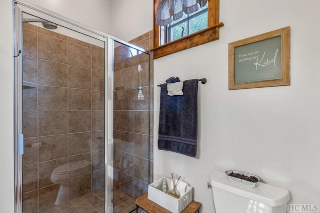 bathroom featuring toilet and a shower with door