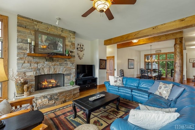 living room with a fireplace, beamed ceiling, wood-type flooring, and ceiling fan with notable chandelier