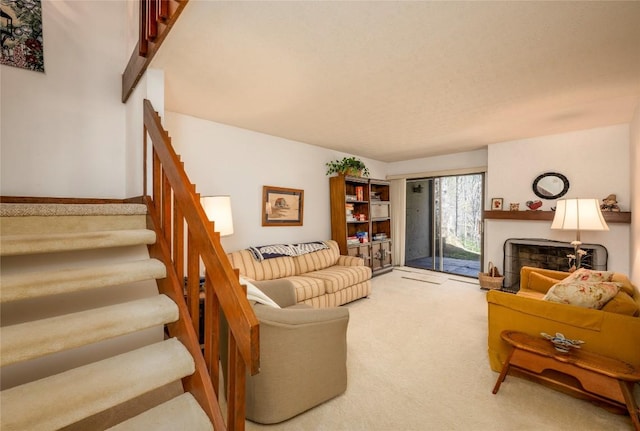carpeted living room featuring stairway and a fireplace