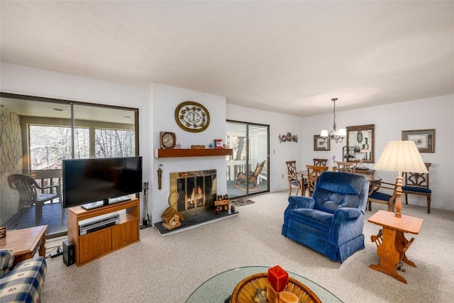 living room with a glass covered fireplace, a notable chandelier, and carpet floors