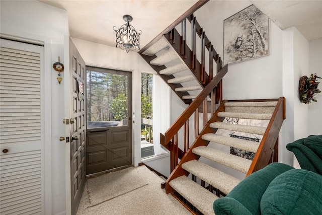 carpeted foyer with a notable chandelier and stairs