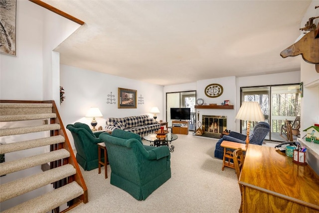 living room with a glass covered fireplace, stairway, and carpet floors